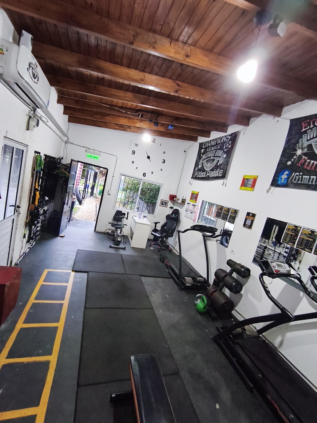 Zona de entrenamiento con cinta, bicicleta fija y escalera de agilidad en Motivate Gym